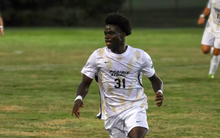 Brandon Djenebia playing soccer in white and gold UIS uniform