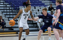 Jordan Rice playing basketball in white UIS uniform