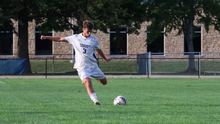 Adam Knaze playing soccer at UIS in white uniform