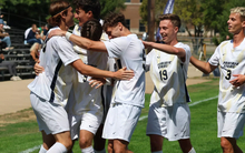UIS men's soccer athletes in white UIS uniforms celebrate a goal