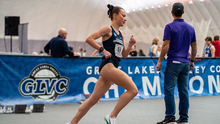 Madelyn Miller-Ross running indoor track in blue UIS uniform