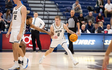Britton Dutton playing basketball in white UIS uniform