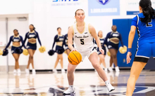 Julia Mingus playing basketball at UIS in white uniform