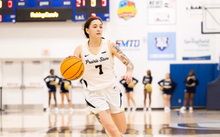 Kennedy Osterman playing basketball in white UIS uniform