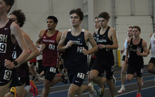 Owen Whelan running indoor track in blue UIS uniform