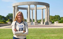 Alyssa Hasler poses in front of UIS Colonnade in gold volleyball uniform