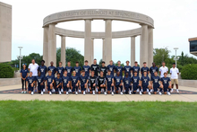 Team photo of UIS mens soccer team in blue uniforms, along with staff