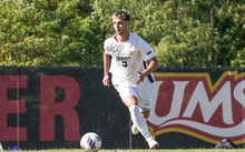 Adam Knaze playing soccer in white UIS uniform