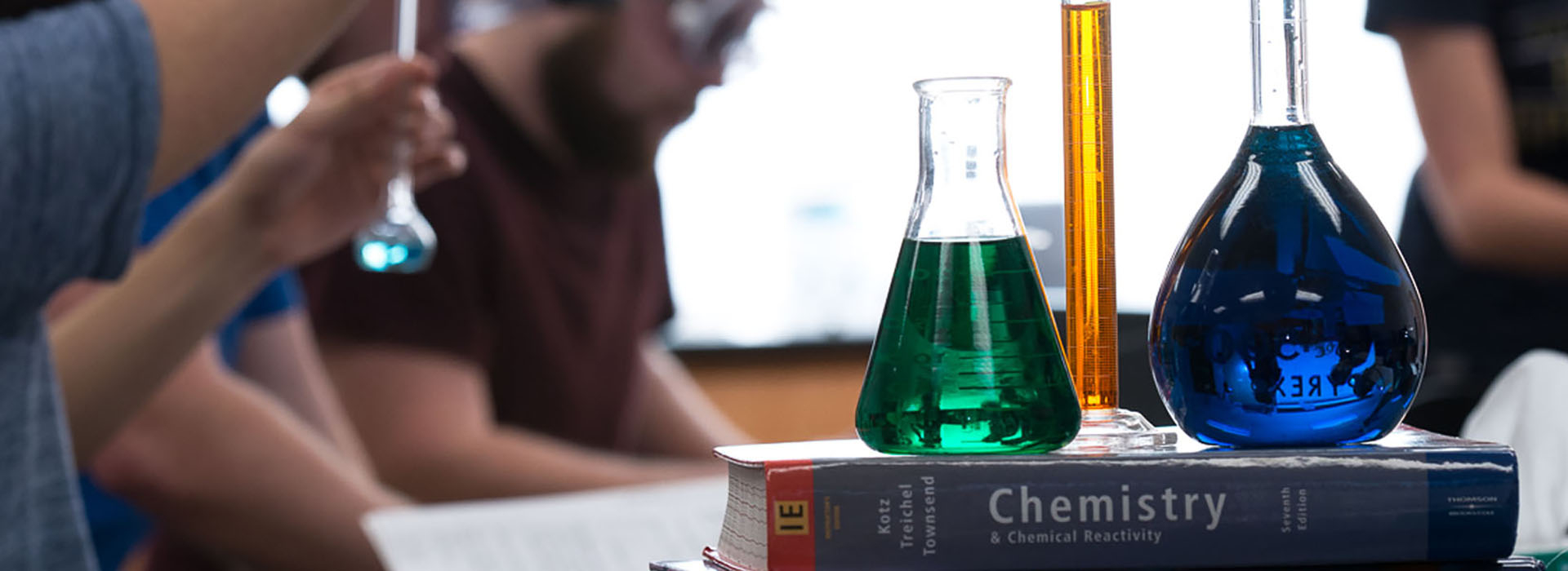 a chemistry classroom with filled beakers sitting on a closed textbook