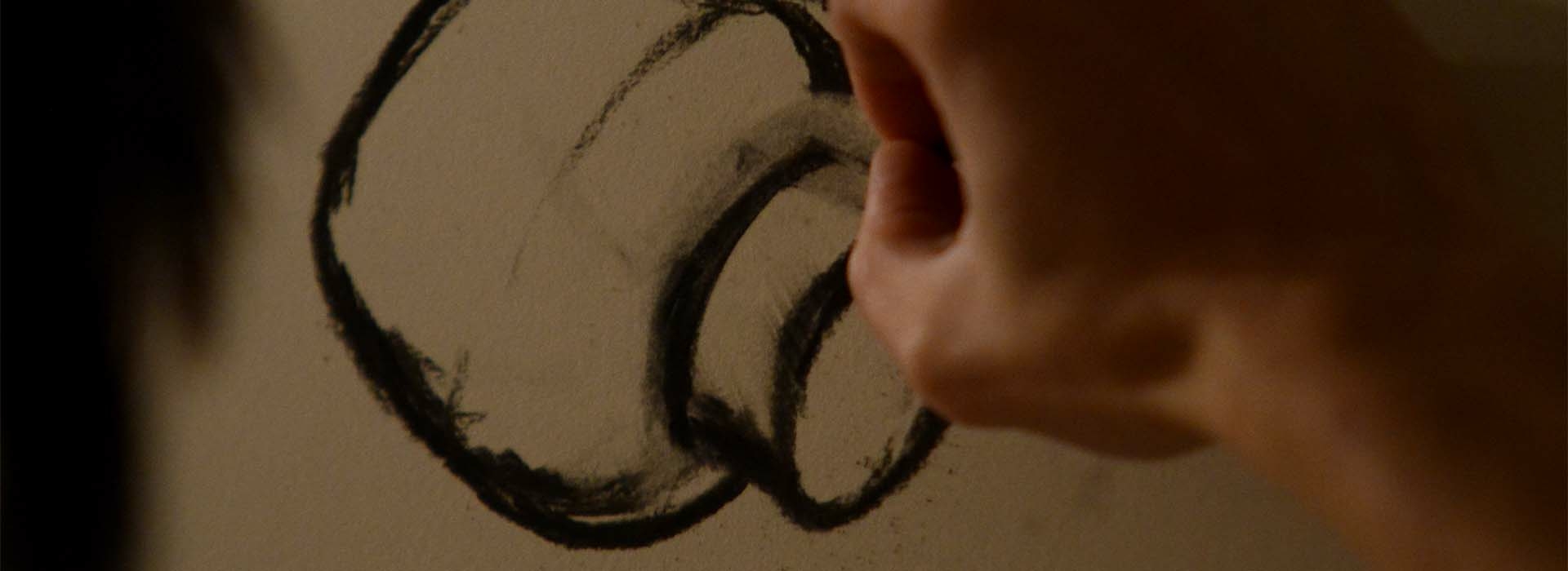 Hand creating a charcoal drawing.