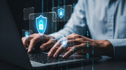 Hands typing on a laptop with digital security icons.