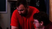 Two men discussing something on a laptop, one pointing at the screen.
