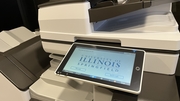 Printer with a touchscreen display featuring a university logo.