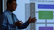Man presenting data flowchart on screen.