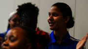 People clapping in a dimly lit room, wearing casual blue shirts.