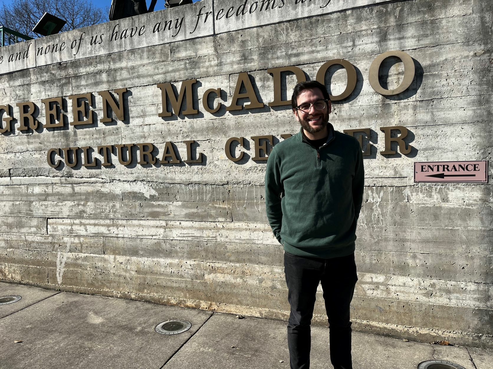 Adam Velk stands in front of the Green McAdoo Cultural Center welcome sign