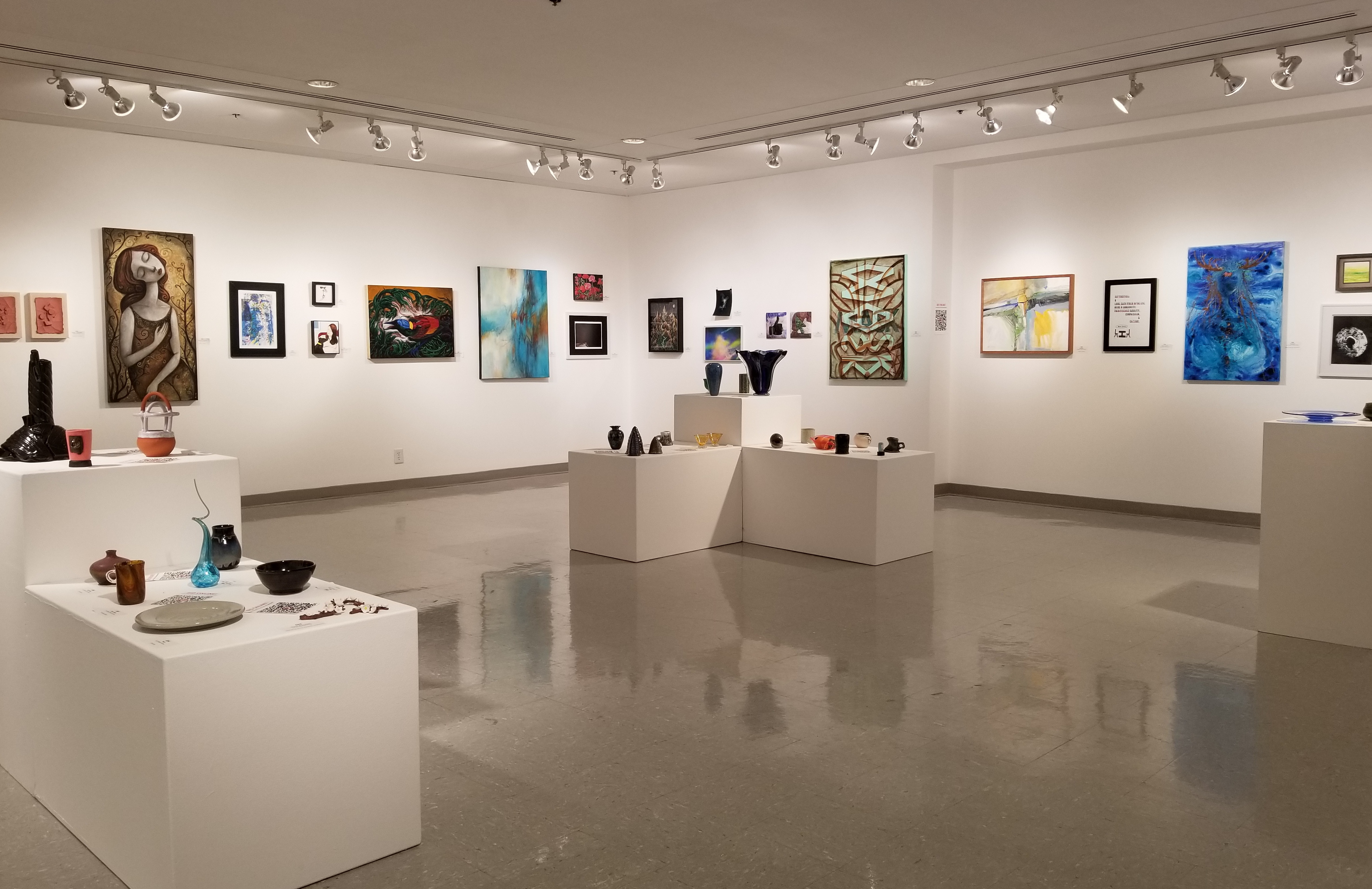 interior shot of art gallery with artwork hanging on walls and sitting on pedestals