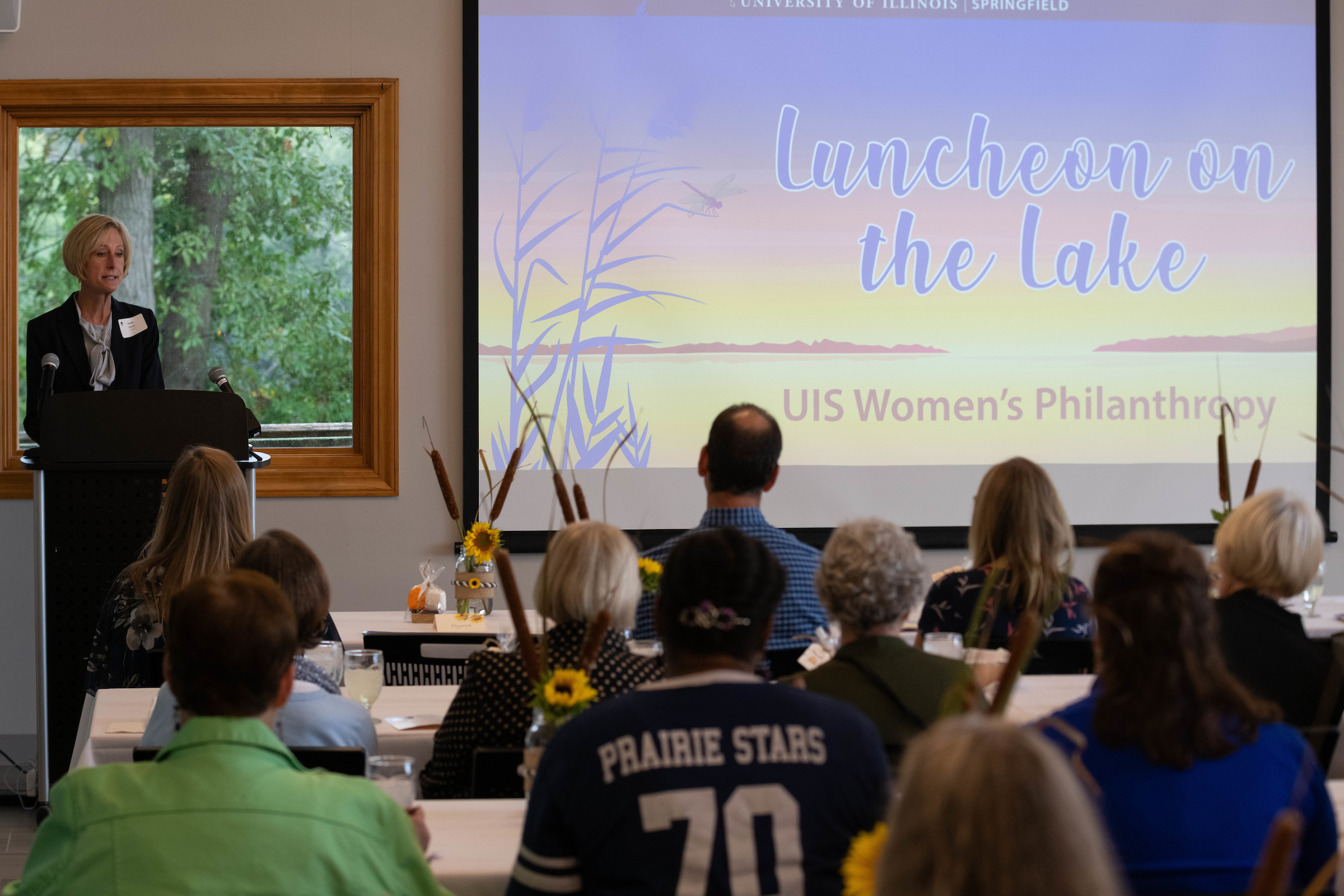 UIS Chancellor addresses a room of people at a luncheon on the lake