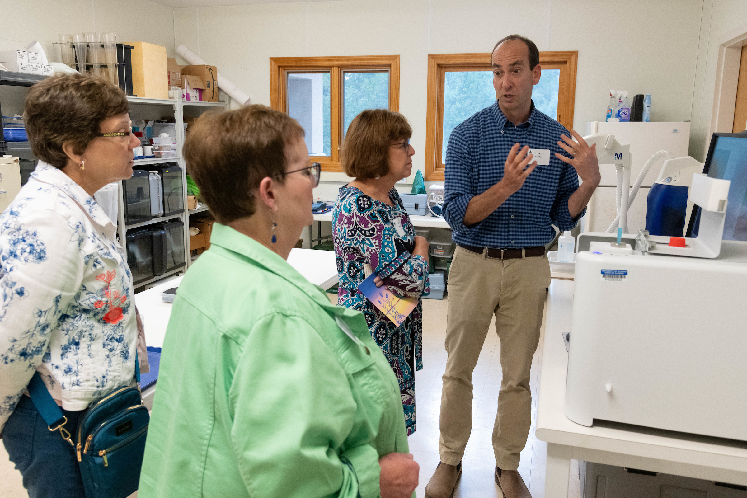 Three women are shown some laboratory equipment by a male professor