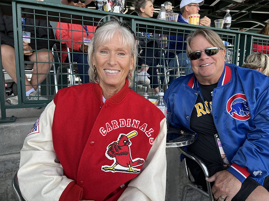 Two people smile as they sit in their seats enjoying a baseball game