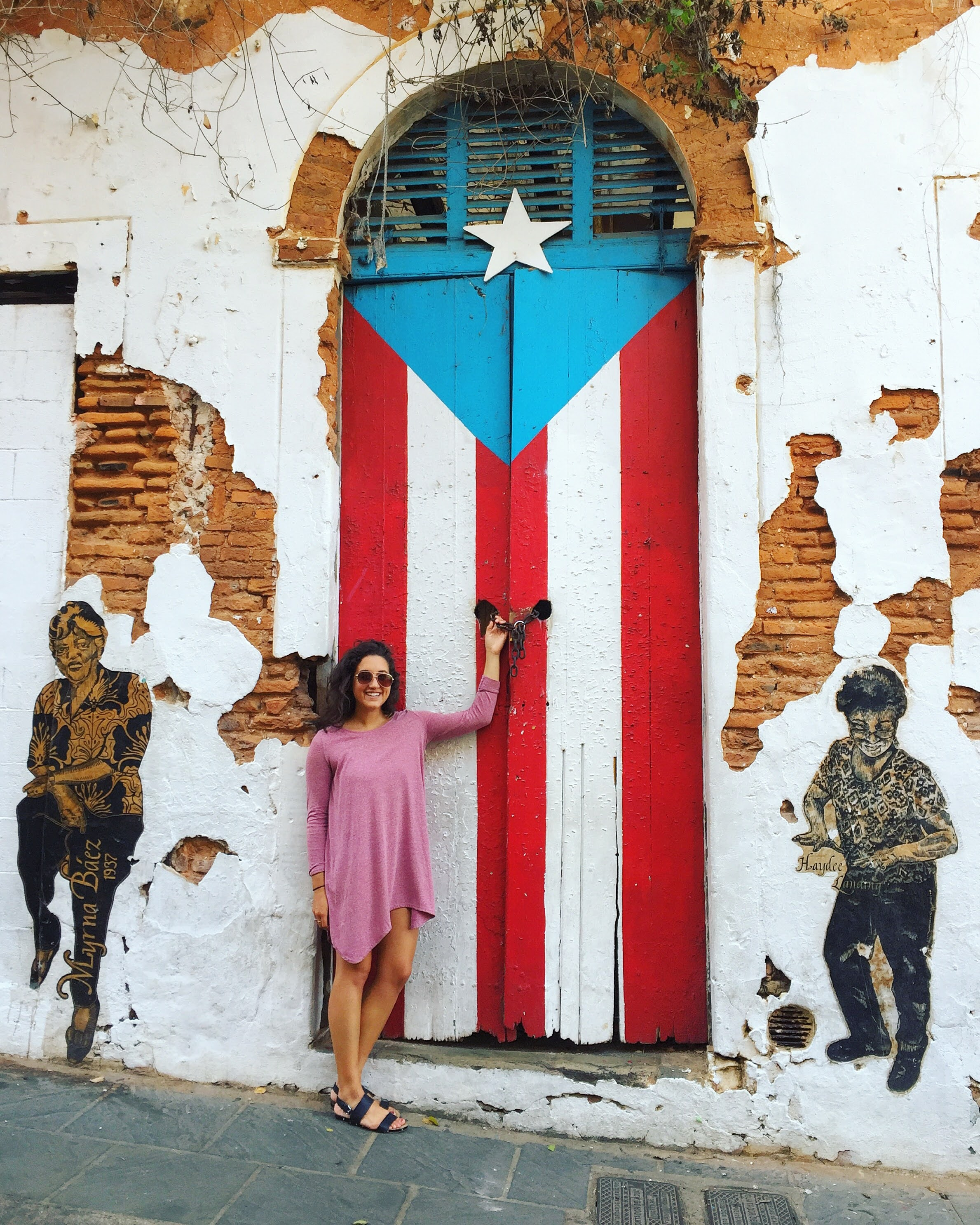 Female student posing in front of a door painted with the Puerto Rico flag