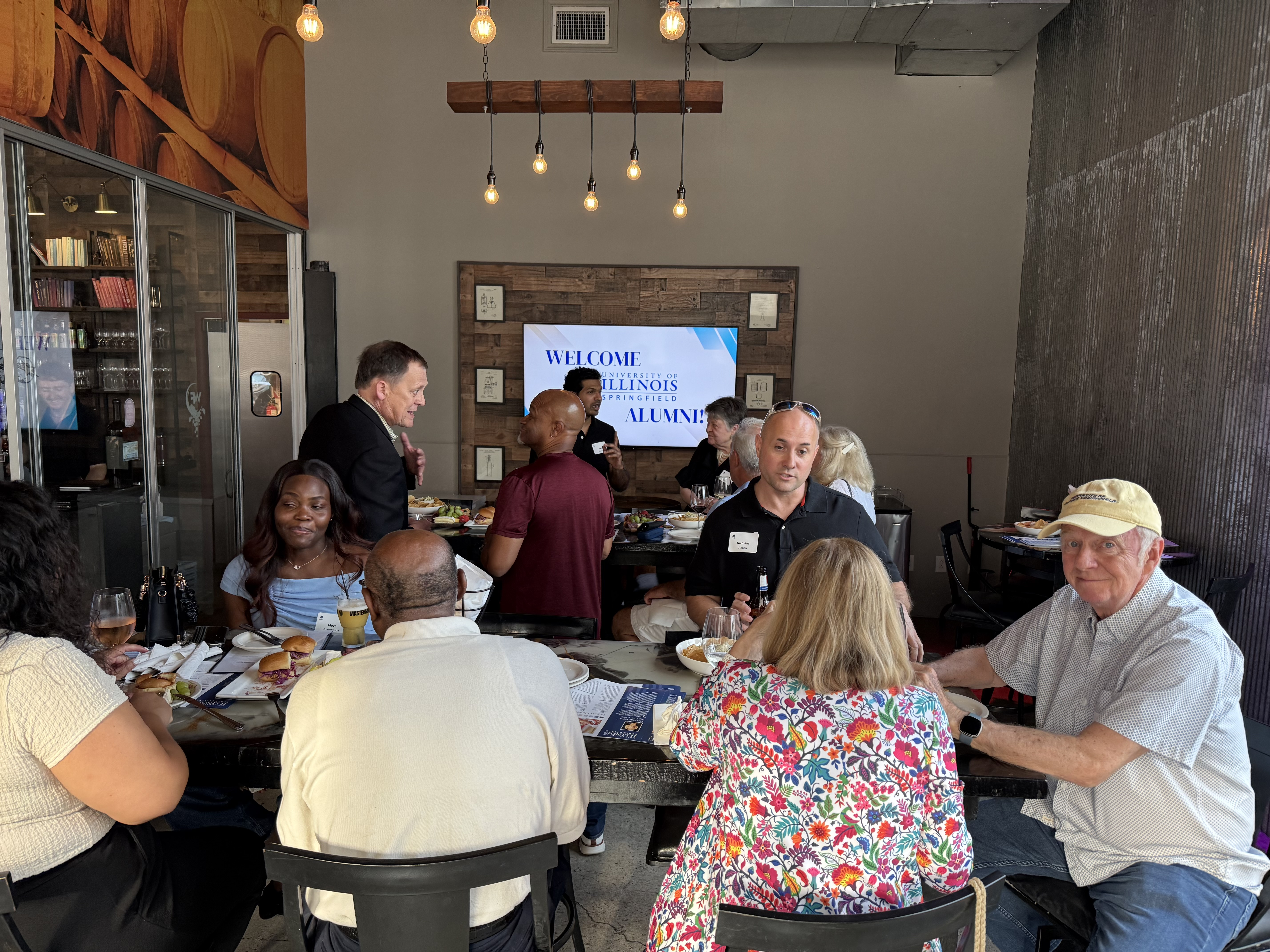 Gathering in a dimly lit room with people seated around tables.