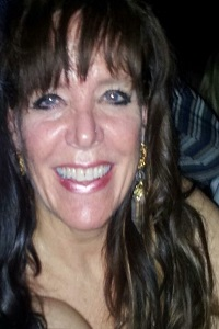 Smiling woman with long dark hair and gold earrings.