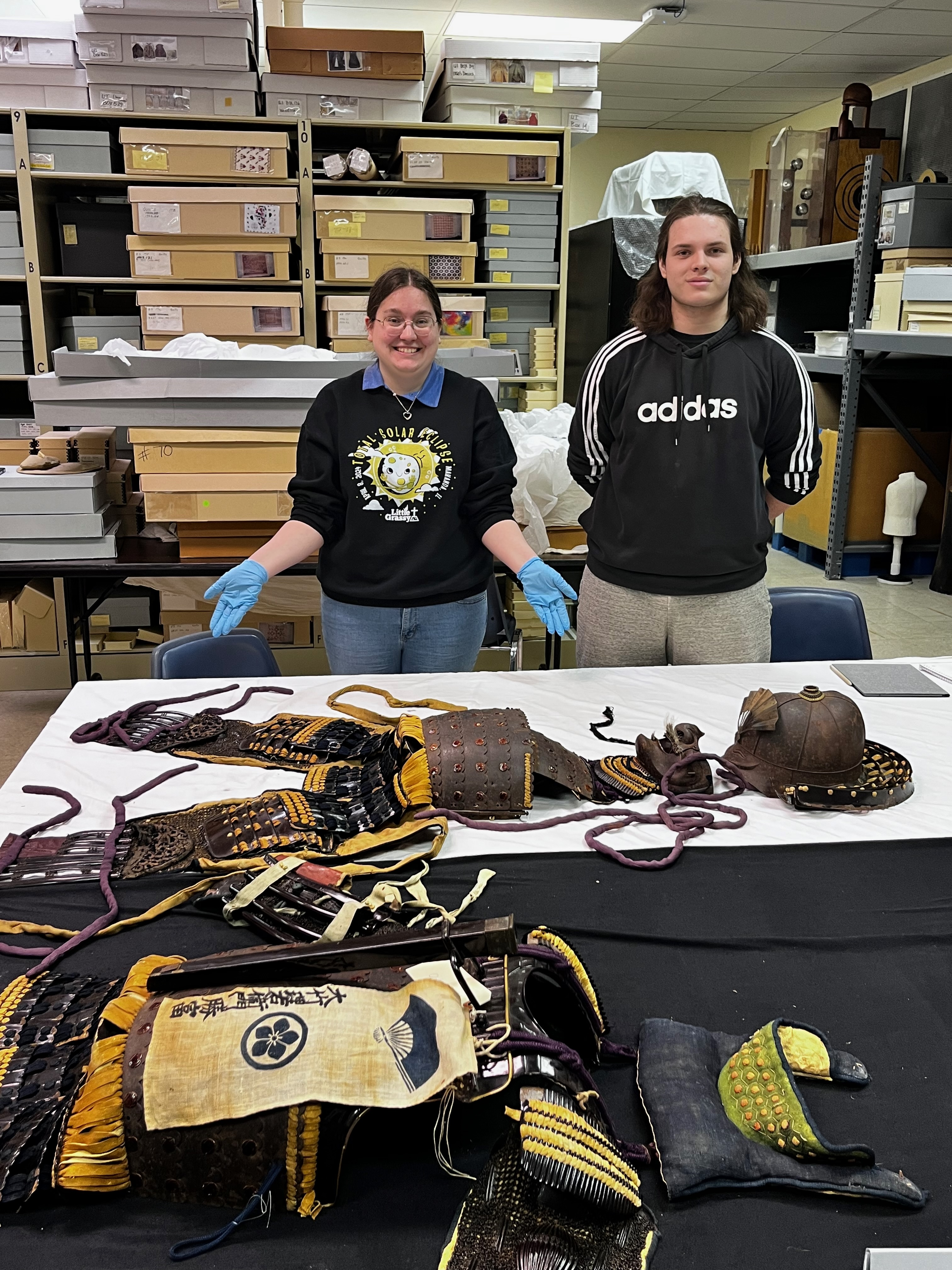 Two people stand behind a table displaying historic Japanese armor.