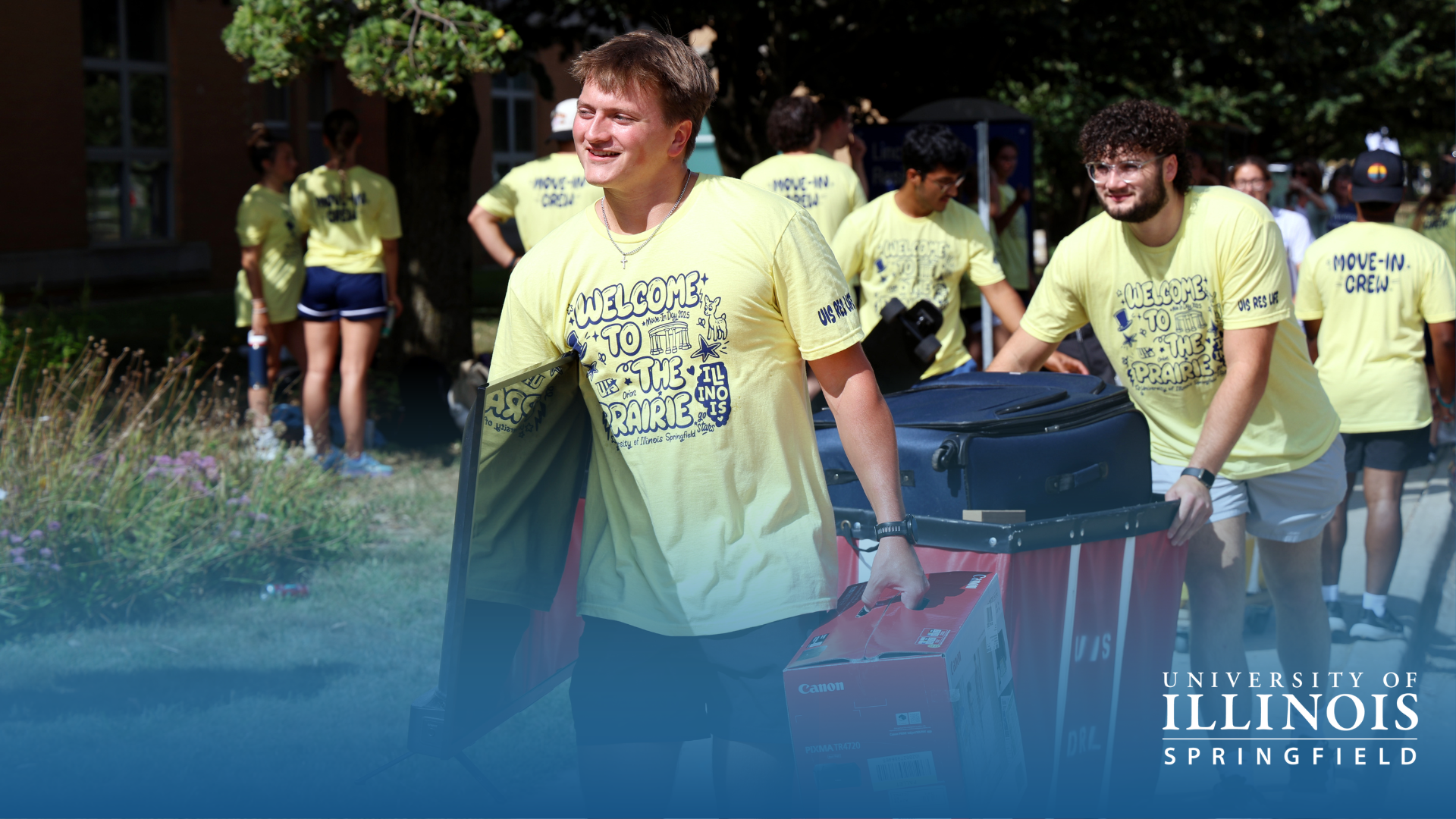 Students in yellow shirts moving carts outdoors.