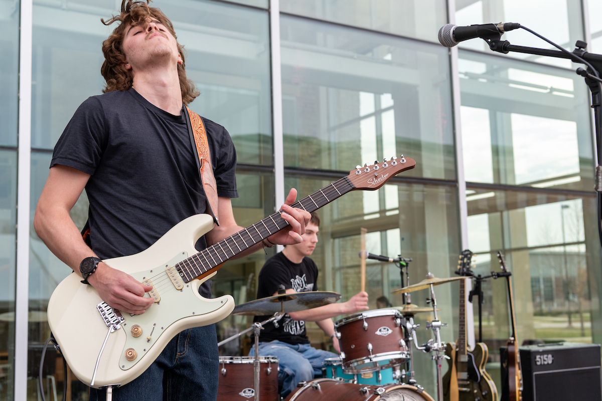 Man rocks out while playing electric guitar on the student union patio during the UIS Day of Giving kickoff party.