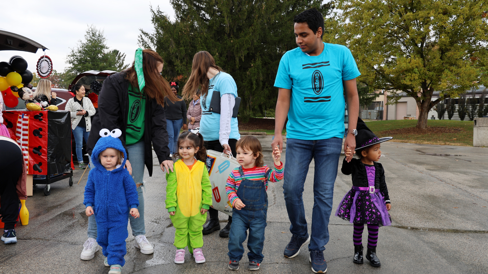 A man on Halloween walking with four small children.