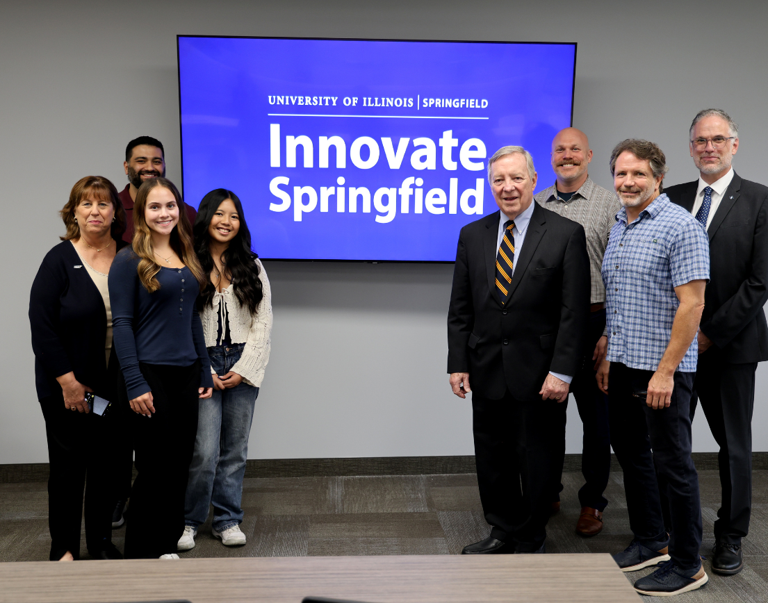 Two groups of people stand in front of a screen that says, "Innovate Springfield."