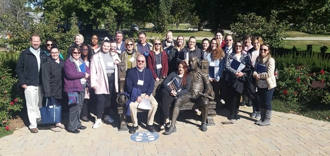 Employees posed for a picture around the Shakespear bench and statue at the Shakespeare Garden.
