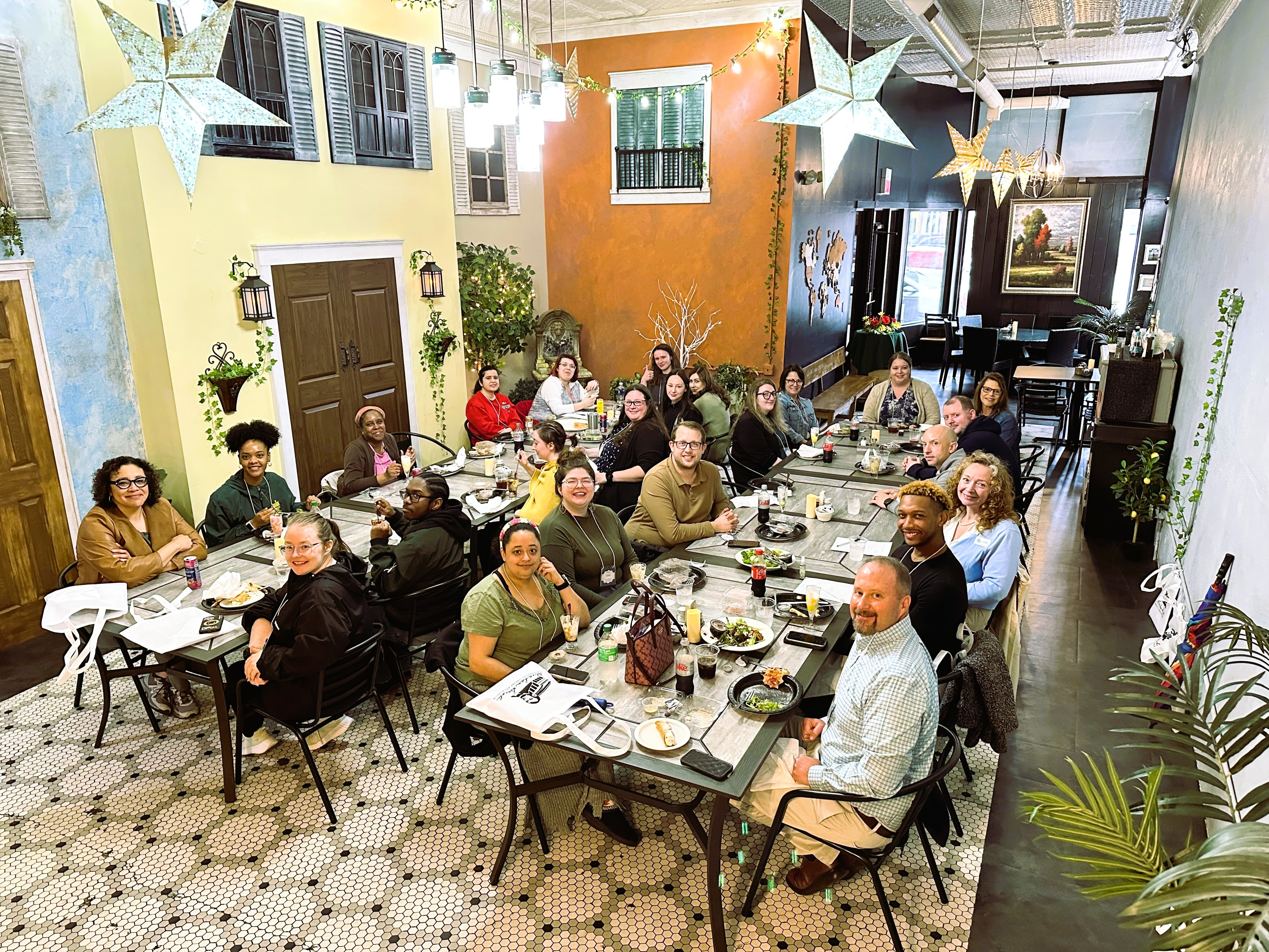 Employees sitting at 2 long tables at a restaurant downtown.