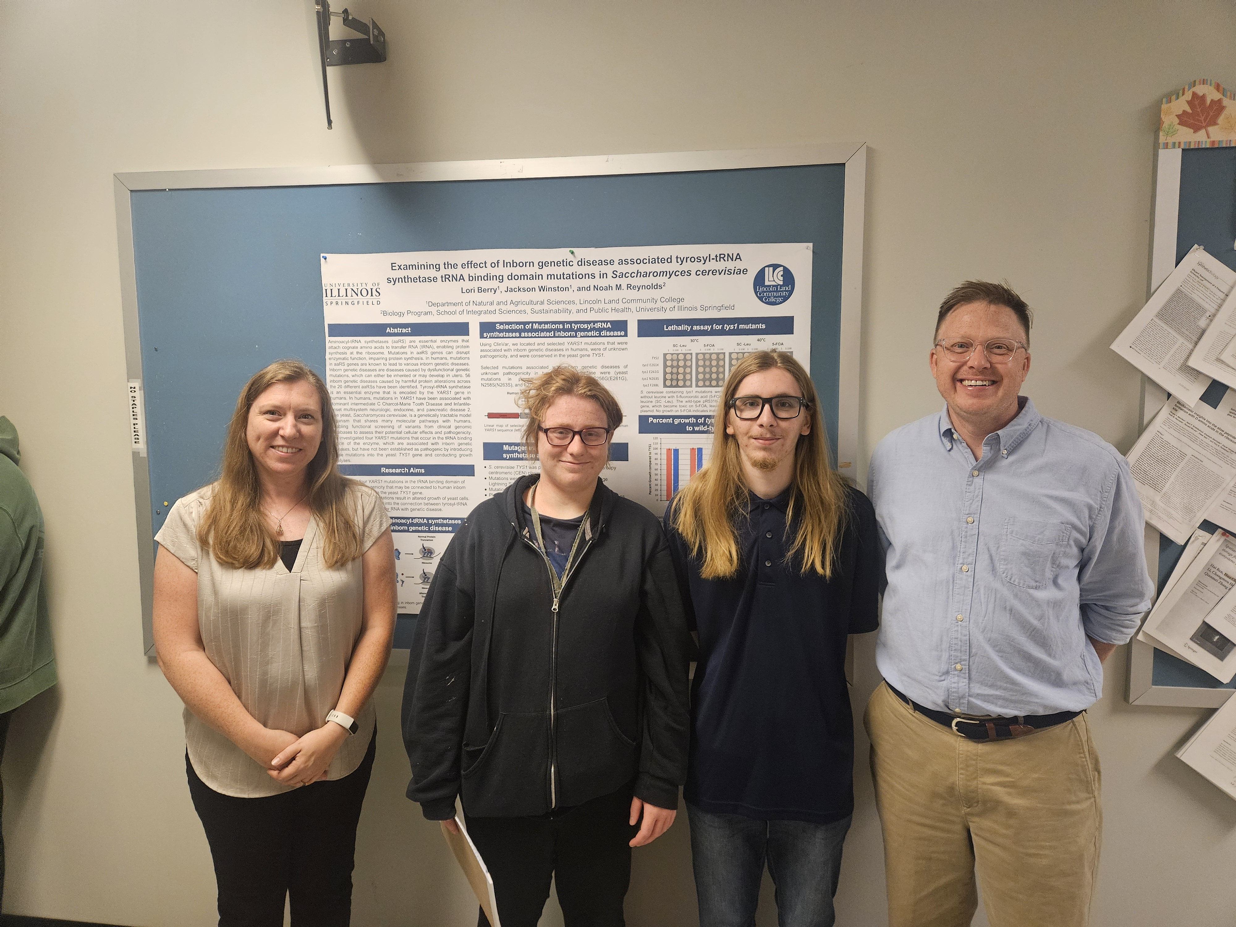 Two students and two faculty members pose beside a biology research poster on genetic disease mutations.