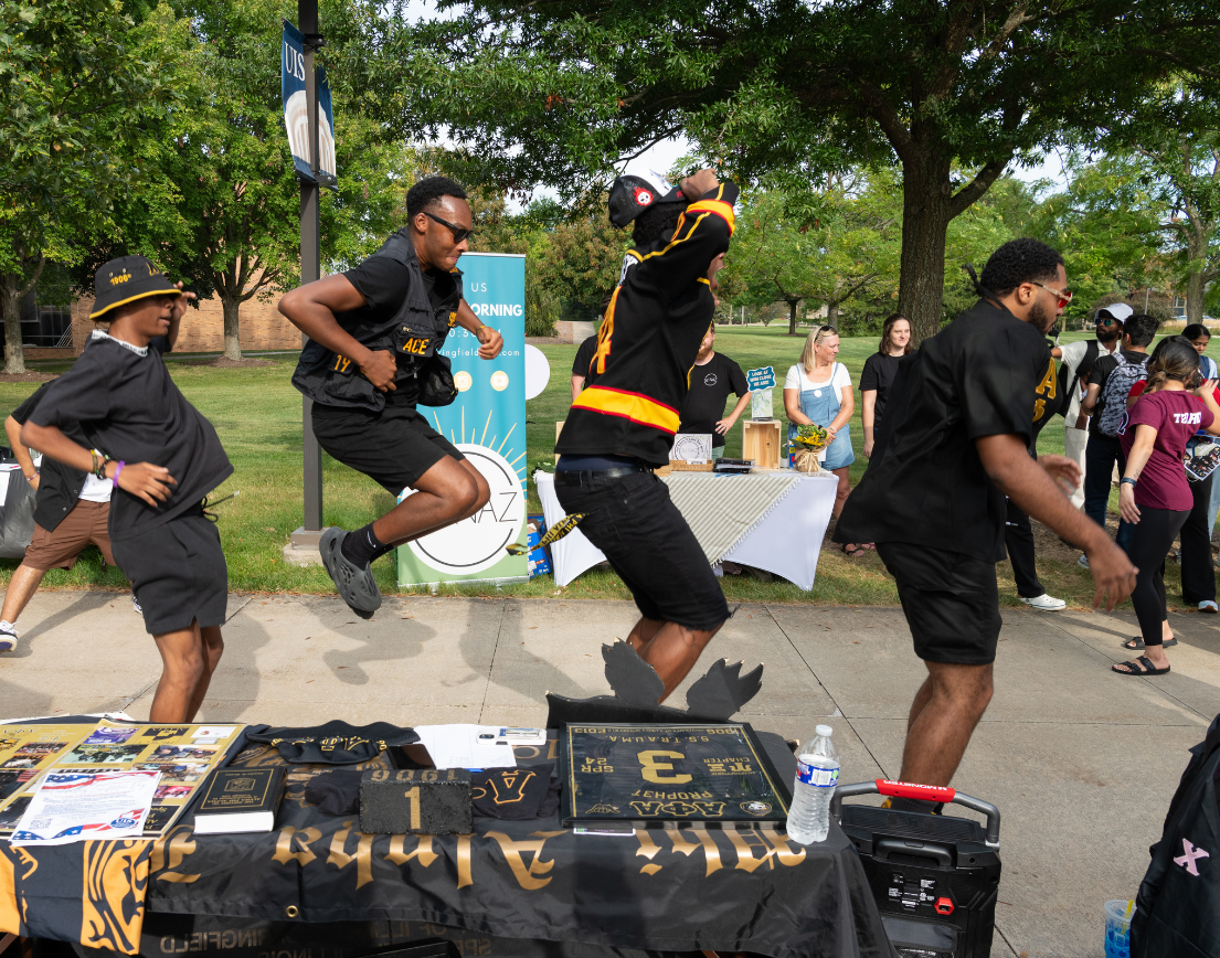 Three men in black and yellow jumping/dancing.
