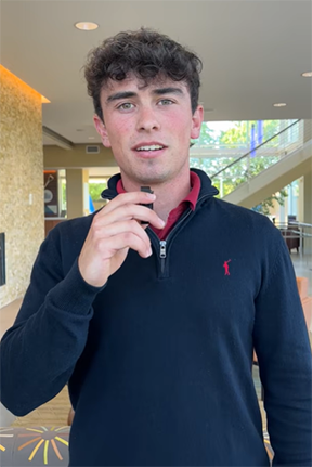 Young man holding a microphone in a modern lobby.