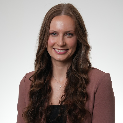 Smiling woman with long brown hair, wearing a maroon blazer.