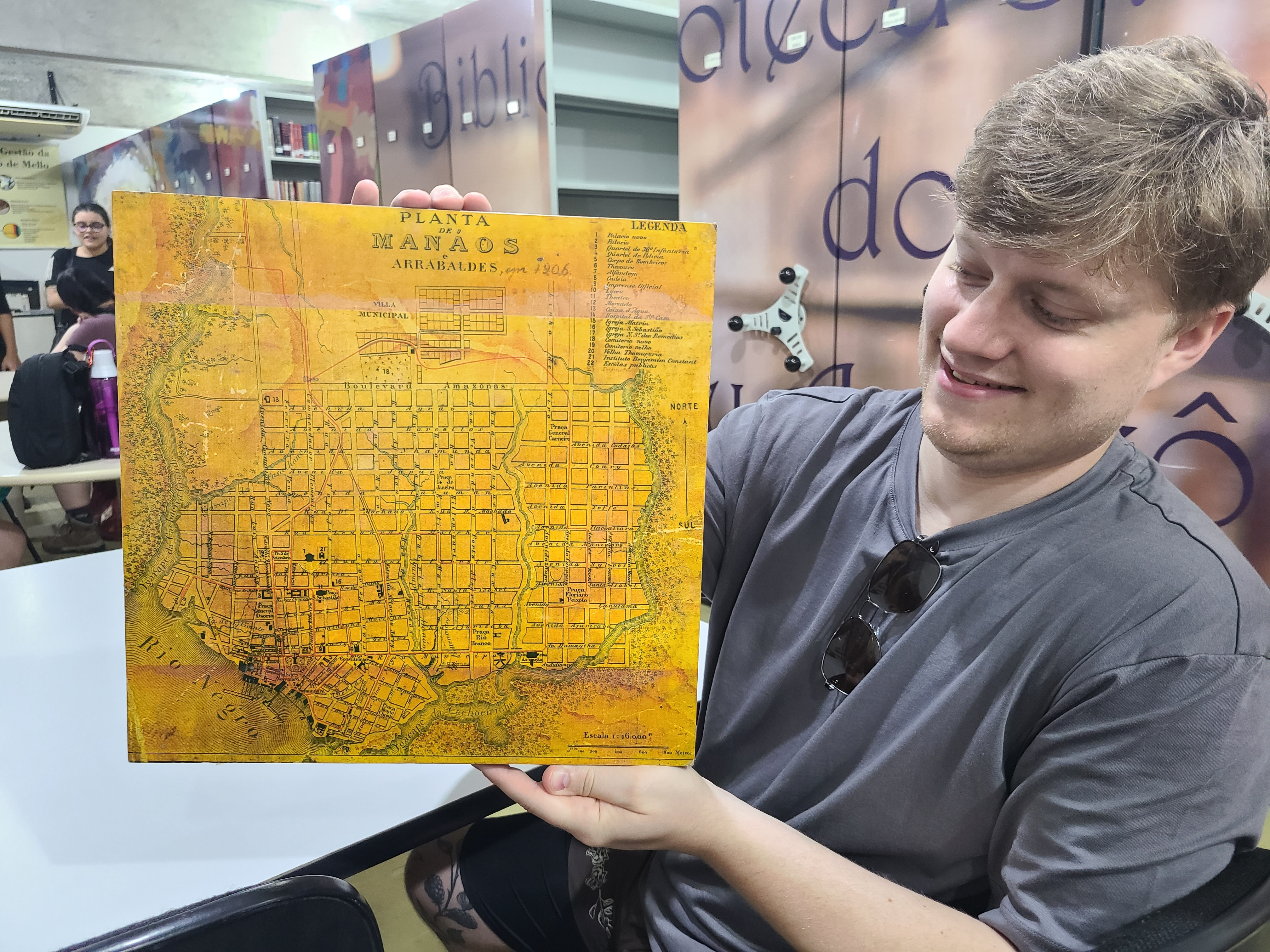A UIS student holds a historic map of Manaus while visiting a library archive in Brazil.