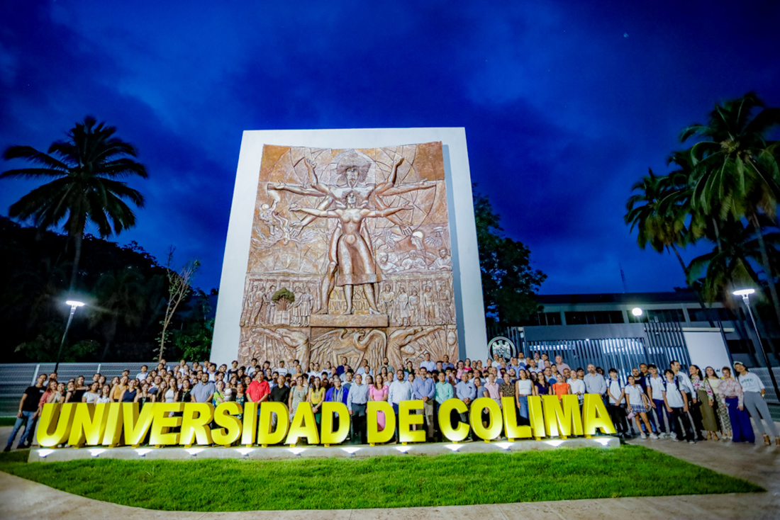 Photo taken at night with a large crowd of people in front of the Colima University sign