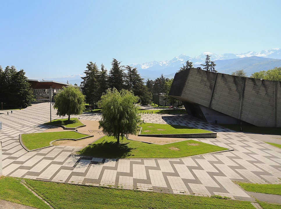 View of UGA campus with geometric pavement, greenery and a modern slanted building. 