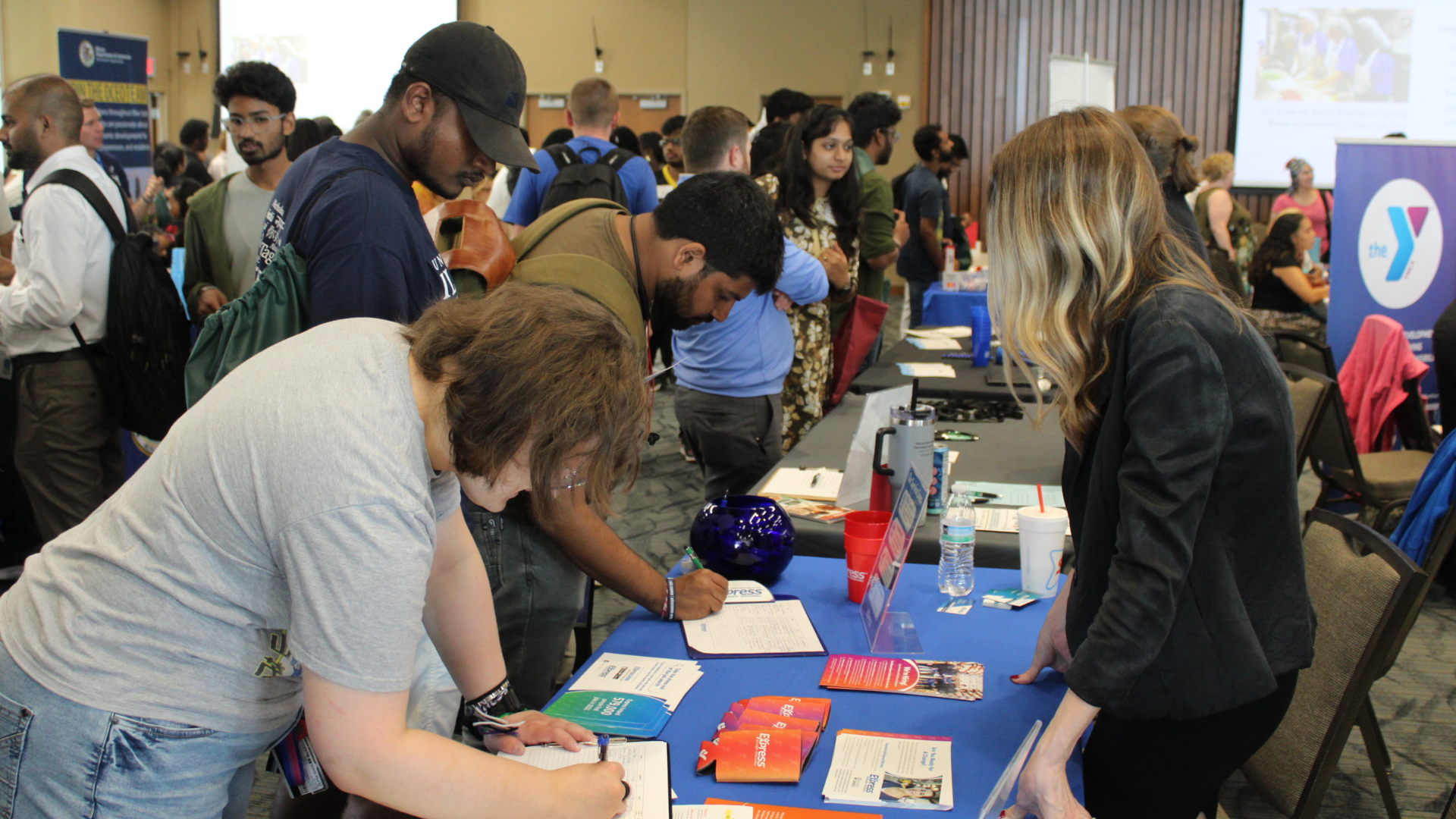 Busy career fair with people interacting at tables.