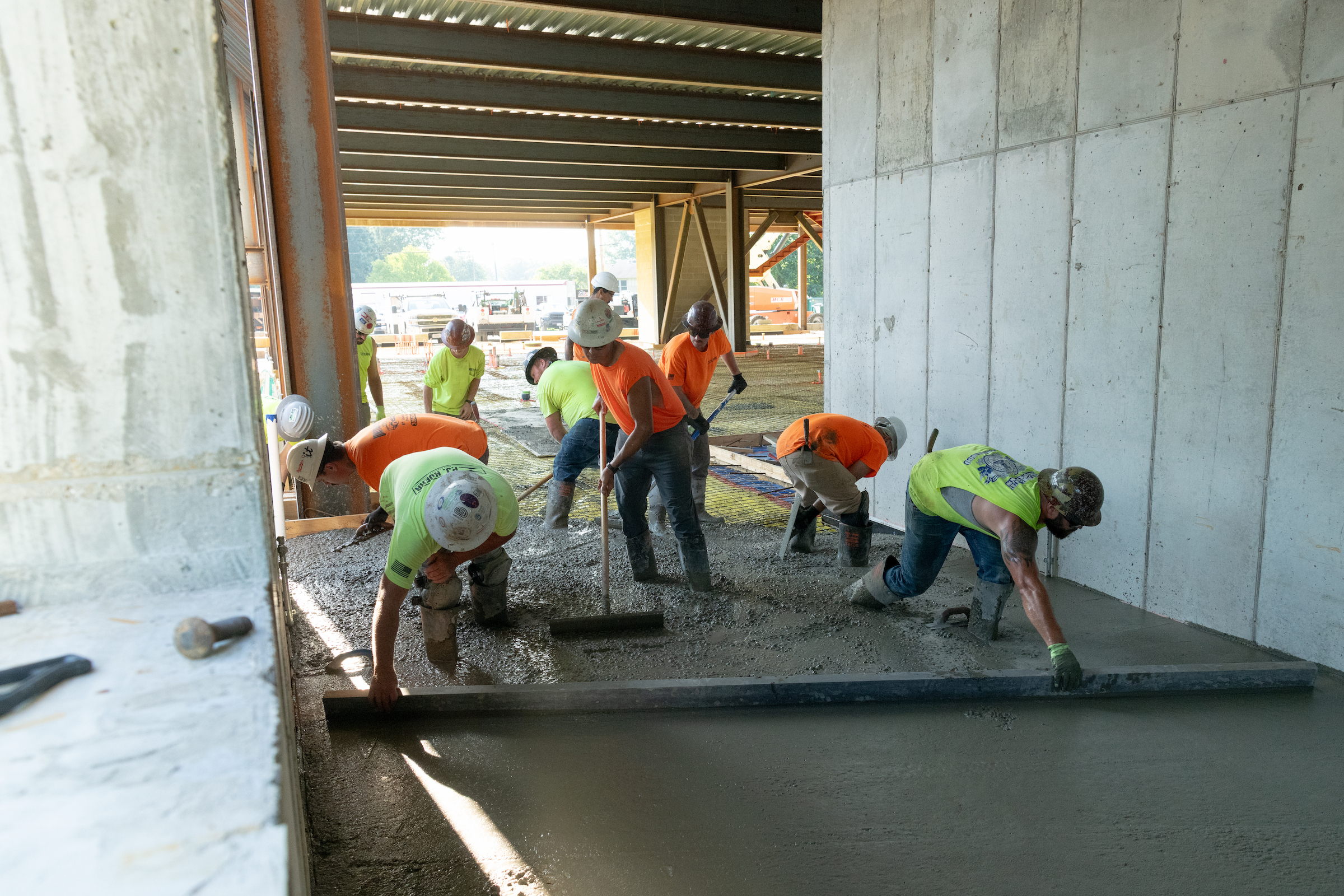 Construction crew members pouring concrete pads