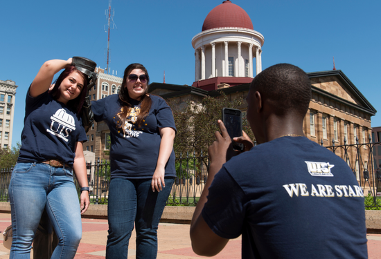 Three people outside posing for a photo in front of a historic building.