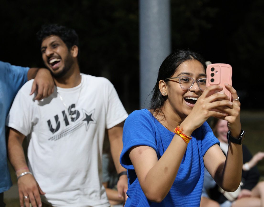 A girl sliming while taking a video on her phone.
