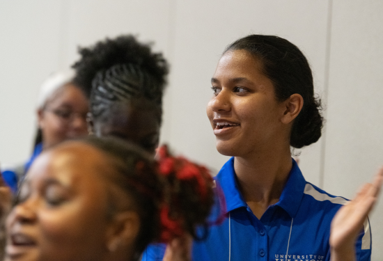 People clapping in a dimly lit room, wearing casual blue shirts.