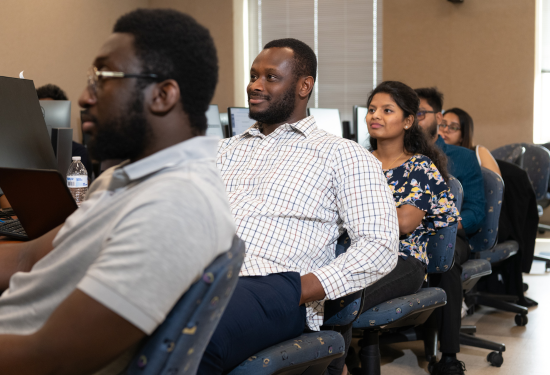 People seated in a classroom, attentively looking forward.