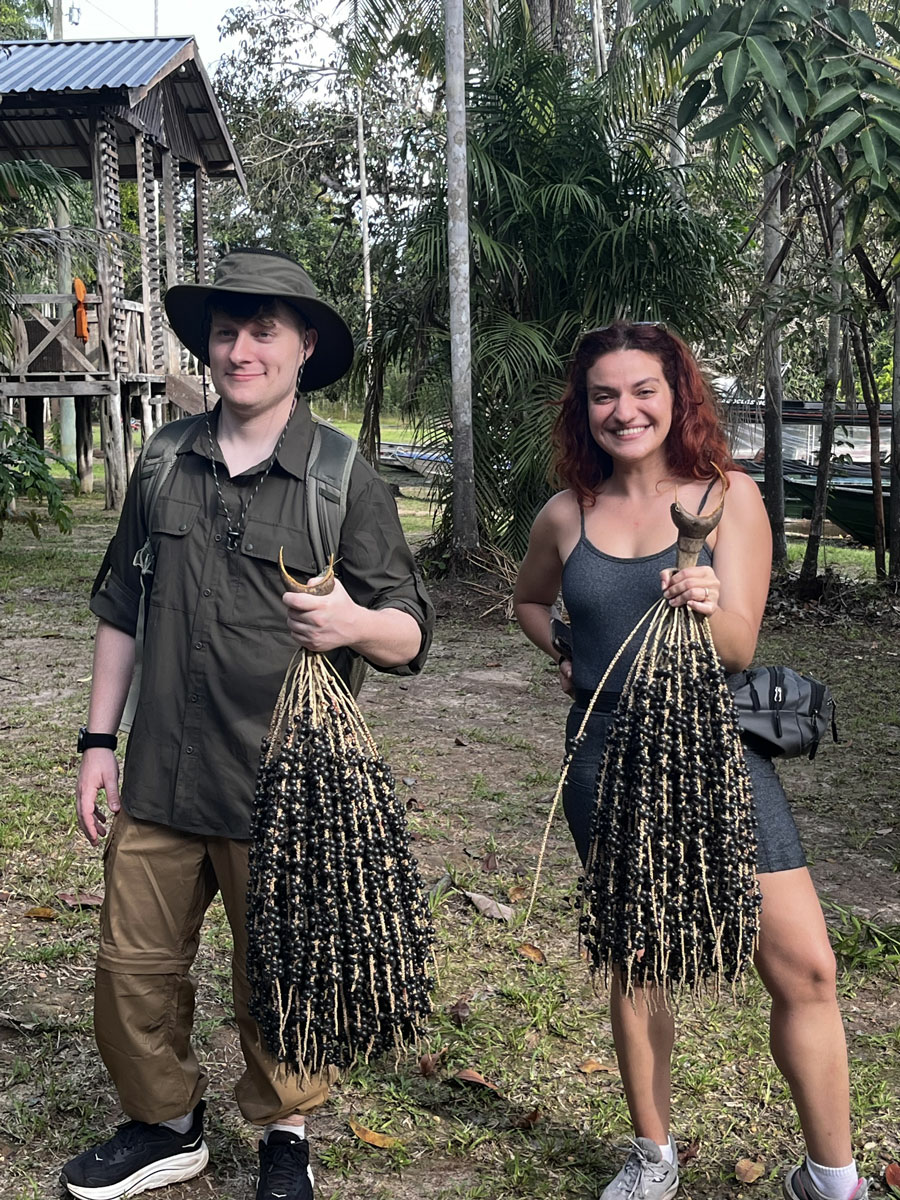 Two students holding large acai berry branches
