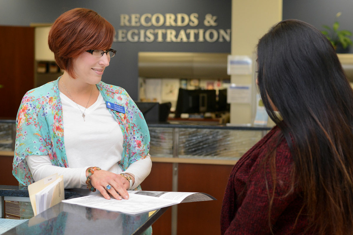 a records and registration employee showing a student how to fill out a form