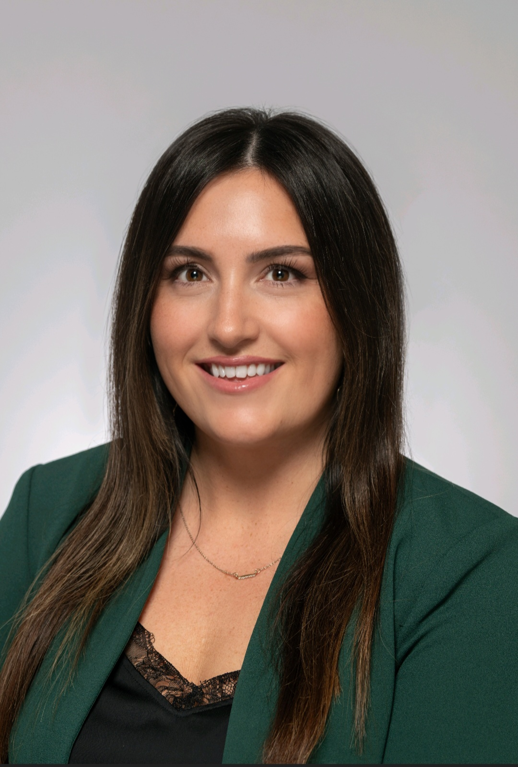 Professional headshot of Brittany Clark smiling against a grey background, wearing a green top.